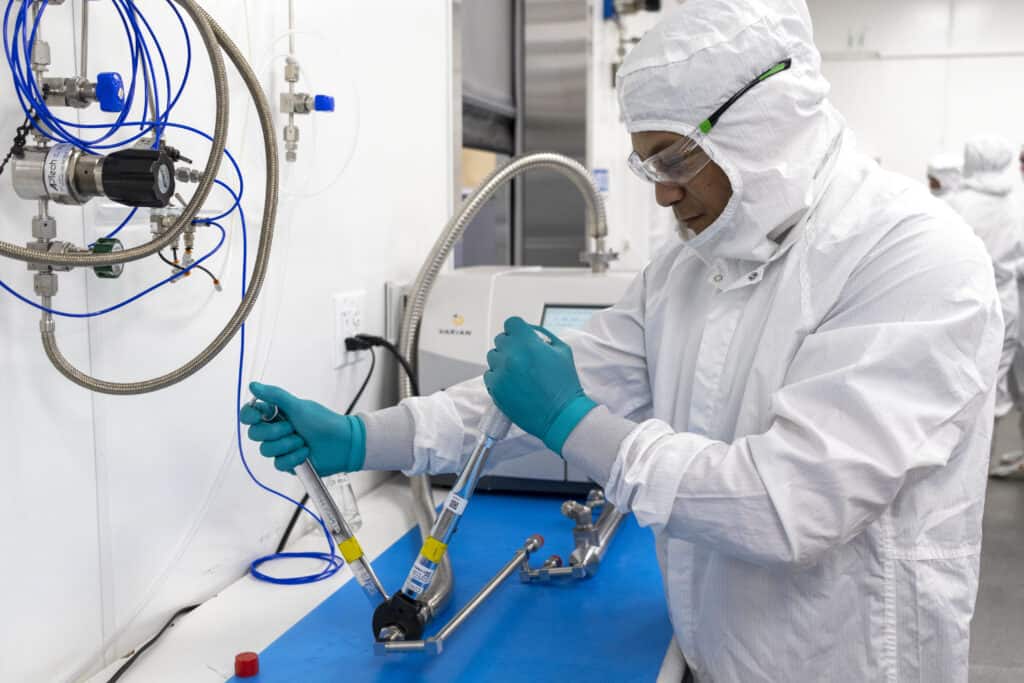 A person in a white clean suit adjusting controls on a clean room.