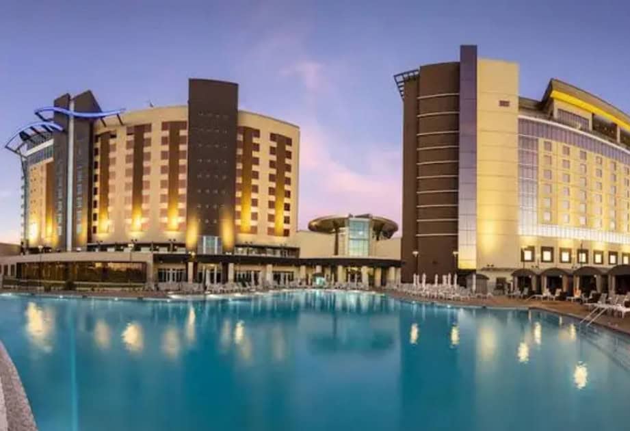 Two buildings, sunset background, pool foreground.